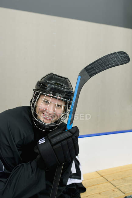 Jugador de hockey sobre hielo sonriente sentado en el banco - foto de stock