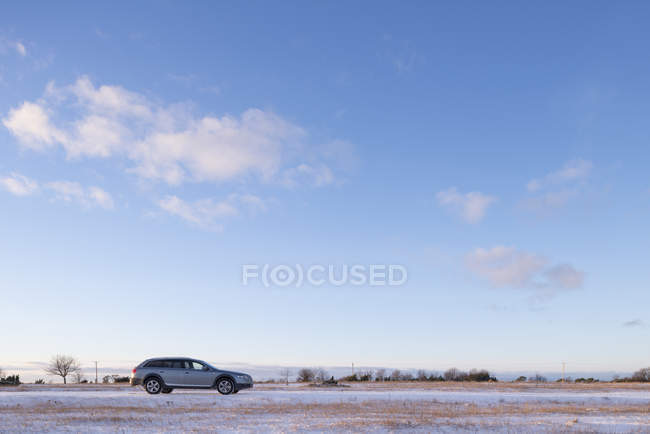 Vista lateral del coche en el campo cubierto de nieve - foto de stock
