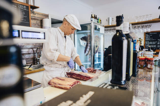 М'ясник нарізає м'ясо в м'ясному магазині — стокове фото