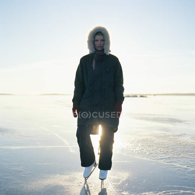 Взрослая женщина на коньках, стоящая на замерзшем озере — стоковое фото
