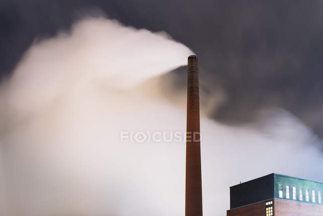 Smoke coming out of smoke stack at factory at night — Stock Photo