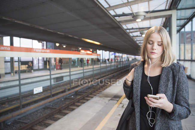 Молода жінка використовує смартфон на станції метро — стокове фото