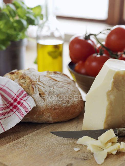 Parmesan cheese and bread on cutting board, differential focus — Stock Photo