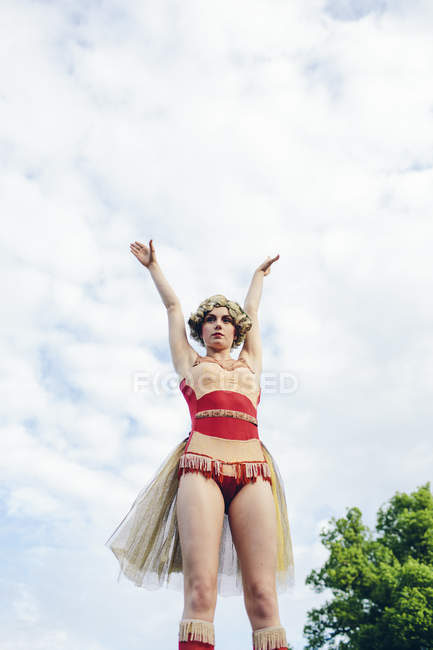 Young female acrobat with arms outstretched against sky — Stock Photo