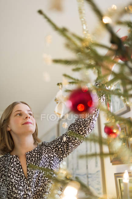 Young woman decorating Christmas tree, selective focus — Stock Photo