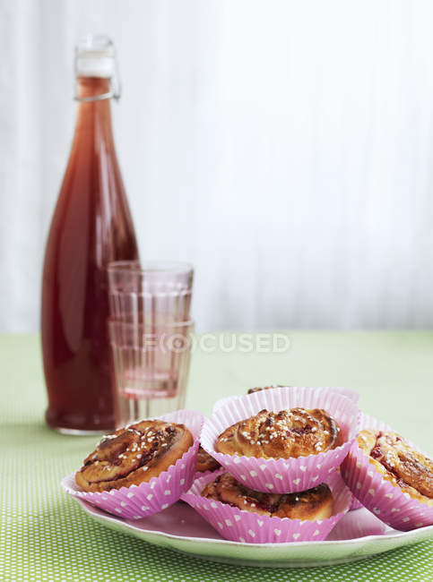 Cinnamon buns and raspberry juice in bottle, selective focus — Stock Photo