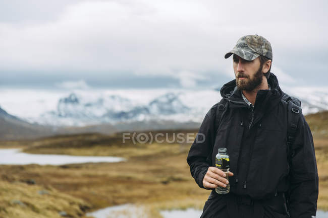 Jeune homme dans les montagnes tenant bouteille en plastique — Photo de stock