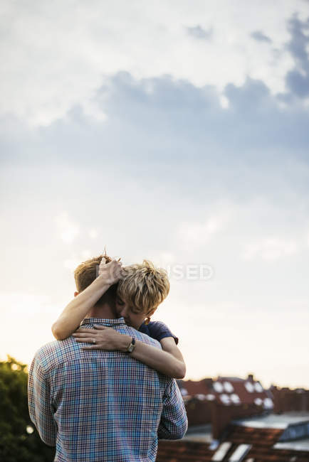 Молода пара обіймається на даху під час заходу сонця — стокове фото