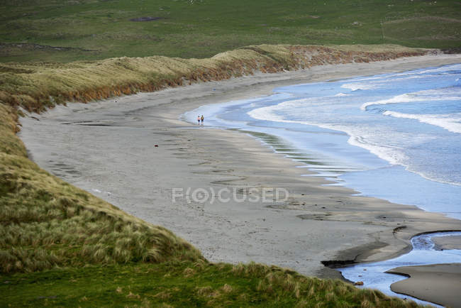 Два человека, идущих по пляжу, выборочное внимание — стоковое фото