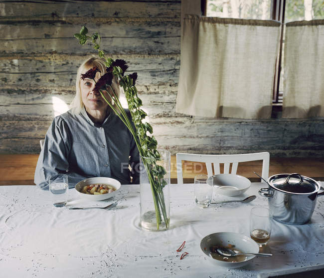 Зрелая женщина с светлыми волосами сидит за столом — стоковое фото