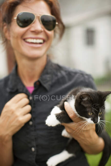Frau hält Katze und lacht — Stockfoto
