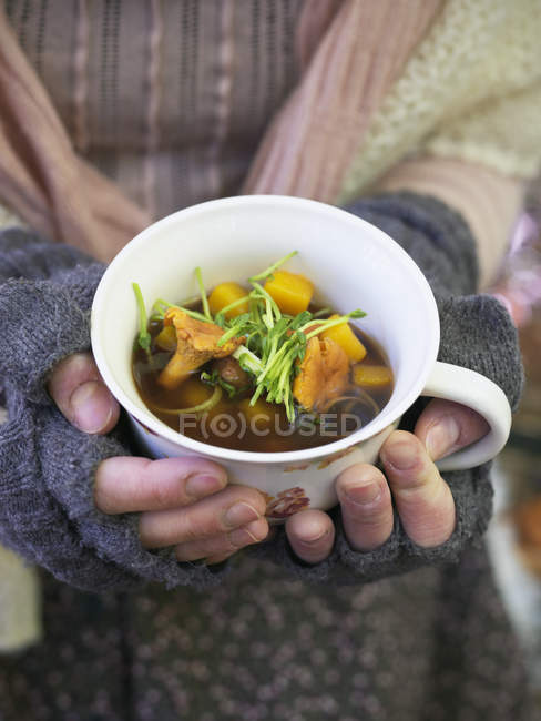 Woman holding mug with mushroom soup, selective focus — Stock Photo