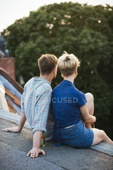 Jeune couple assis sur le toit ensemble — Photo de stock