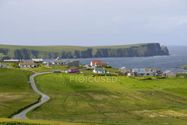 Empty road and village by sea in background — Stock Photo