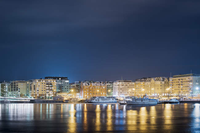 Frente marítimo iluminado con barcos por la noche, norte de Europa - foto de stock