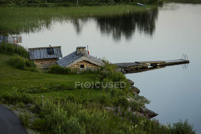Wooden houses and jetty on lakeshore, northern europe — Stock Photo