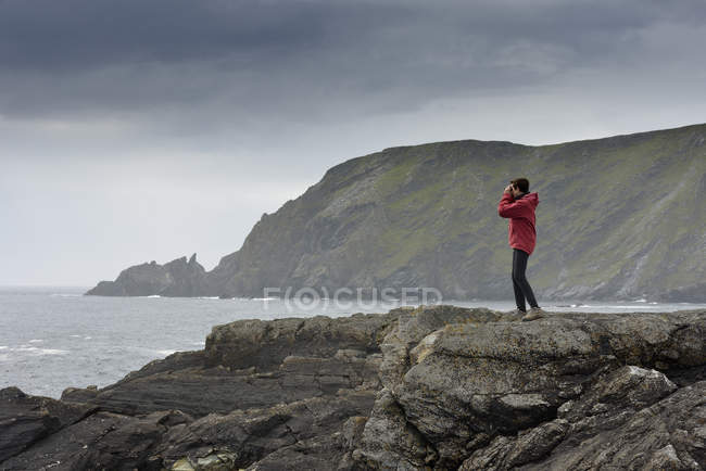 Seniorin steht auf Felsen und blickt auf Aussicht — Stockfoto