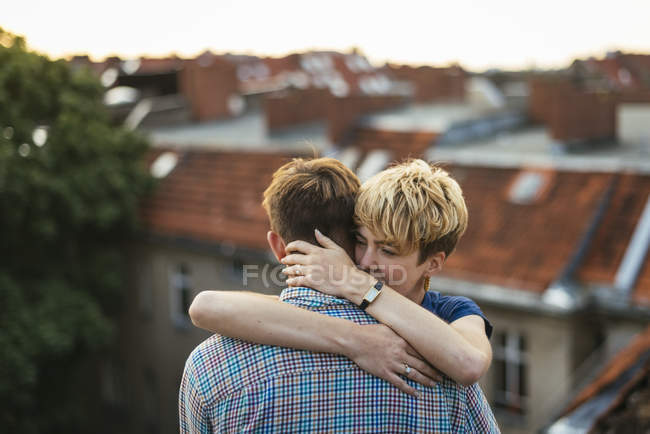 Junges Paar umarmt sich bei Sonnenuntergang auf dem Dach — Stockfoto