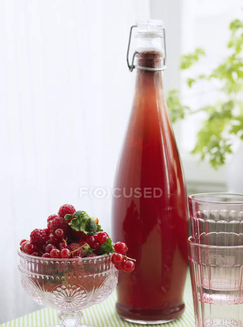 Raspberry juice and bowl of fruits, focus on foreground — Stock Photo