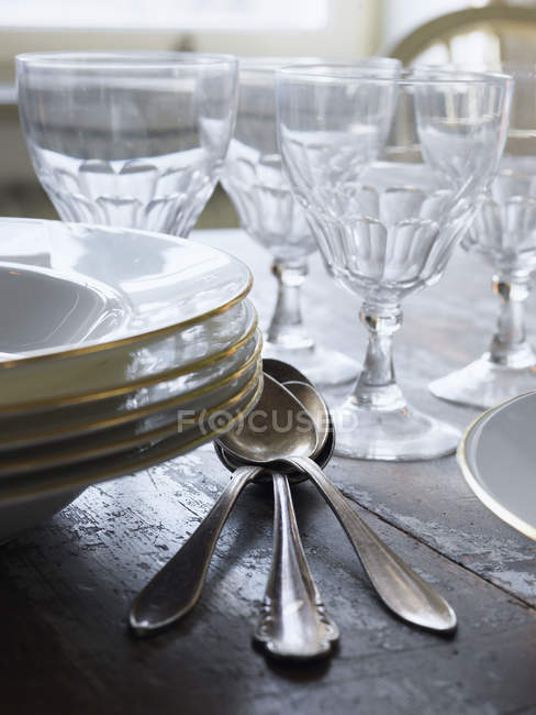 Plates, spoons and drinking glasses on table — Stock Photo