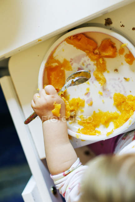 Baby girl eating carrot soup — Stock Photo