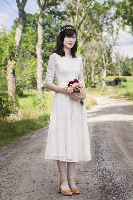 Portrait of bride with bouquet standing on road — Stock Photo
