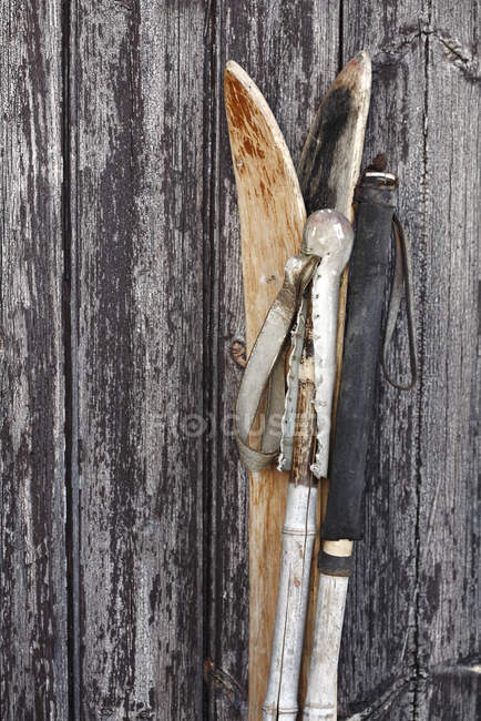 Pair of old skis and poles next to rustic wooden texture — Stock Photo