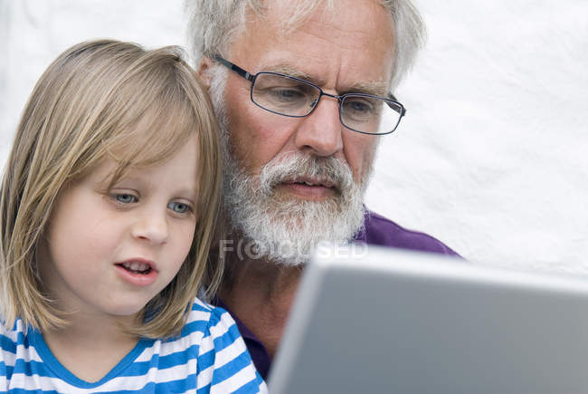 Man with granddaughter using laptop, focus on foreground — Stock Photo