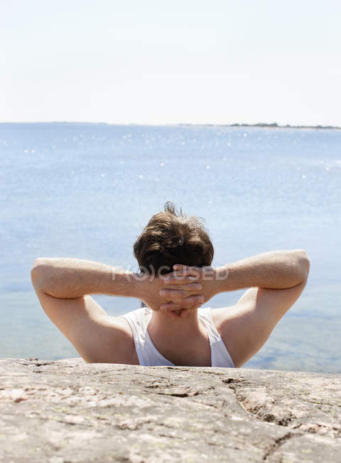 Задний вид человека, отдыхающего на берегу моря — стоковое фото