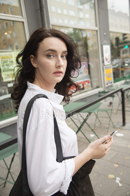 Jeune femme tenant téléphone intelligent — Photo de stock