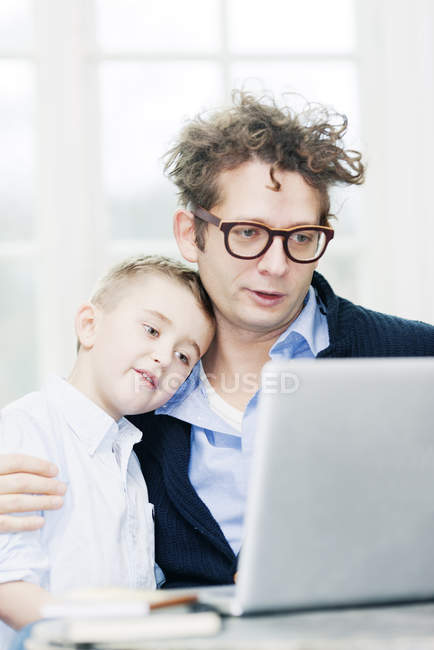 Батько і син носять офіційний одяг за допомогою ноутбука разом — стокове фото