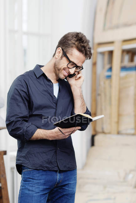 Бізнесмен, дивлячись в організатор під час розмови по телефону — стокове фото