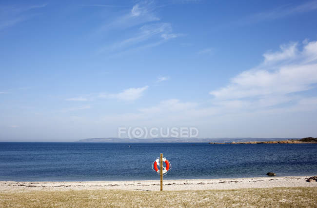 Beach with life belt hanging on pole — Stock Photo