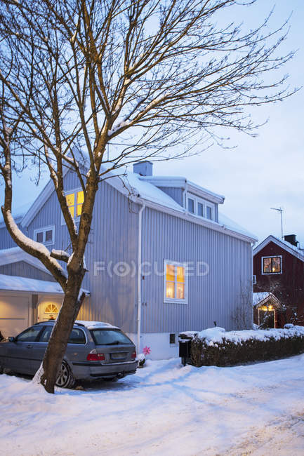 Auto im Winter vor beleuchtetem Haus geparkt — Stockfoto