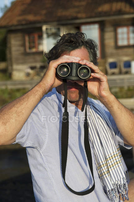 Uomo maturo guardando attraverso il binocolo — Foto stock