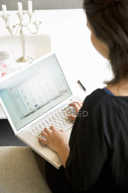 Vista da jovem mulher usando laptop na mesa — Fotografia de Stock