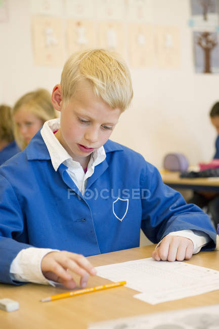 Portrait of schoolboy looking down in classroom — Stock Photo