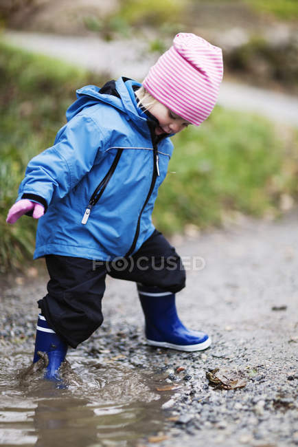 View of girl playing in puddle, focus on foreground — Stock Photo