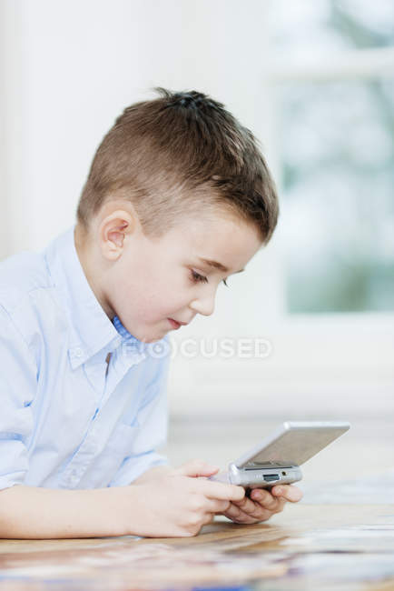 Visão lateral do menino jogando jogo de vídeo portátil — Fotografia de Stock