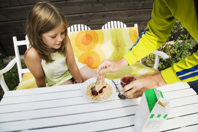Mother serving corn flakes to daughter outdoors — Stock Photo