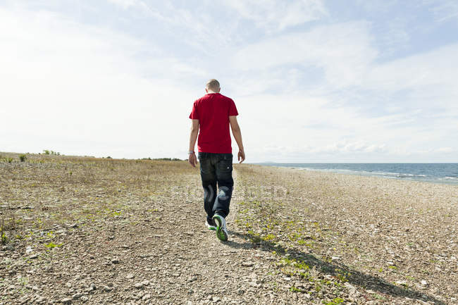 Blick von hinten auf einen jungen Mann, der auf See spaziert — Stockfoto