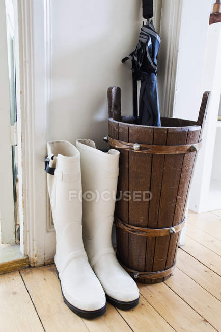Pair of white wellingtons and umbrella indoors — Stock Photo