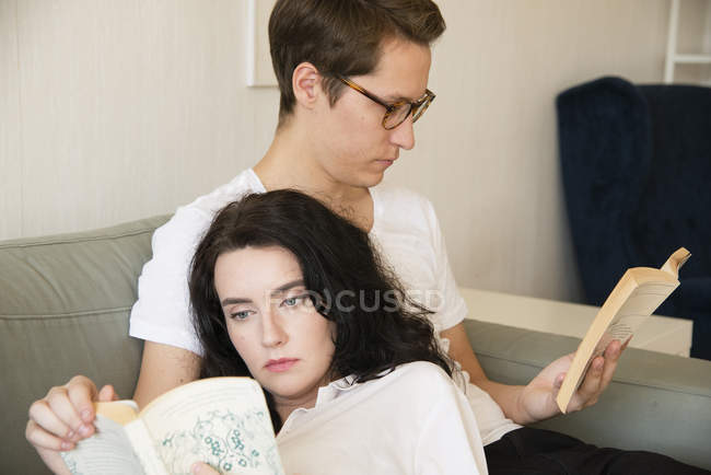 Junges Paar liest Bücher auf dem Sofa, Fokus auf den Vordergrund — Stockfoto