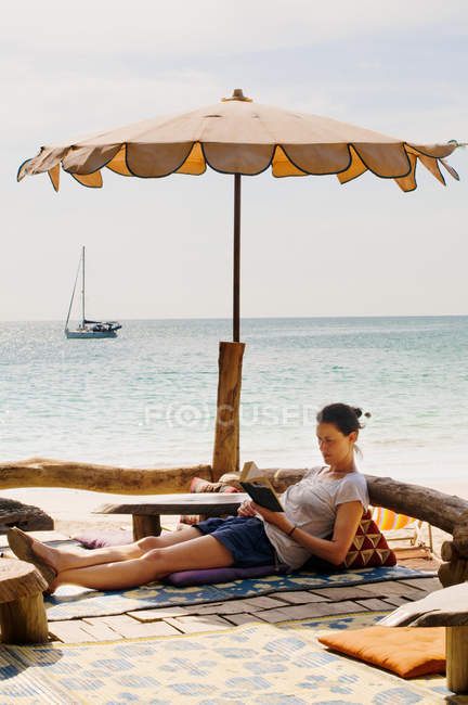 Frau entspannt sich am Strand und liest Buch — Stockfoto