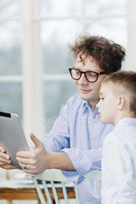 Pai e filho usando camisas usando tablet pc — Fotografia de Stock
