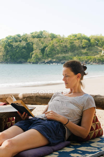 Жінка відпочиває на пляжі і читає книгу — стокове фото