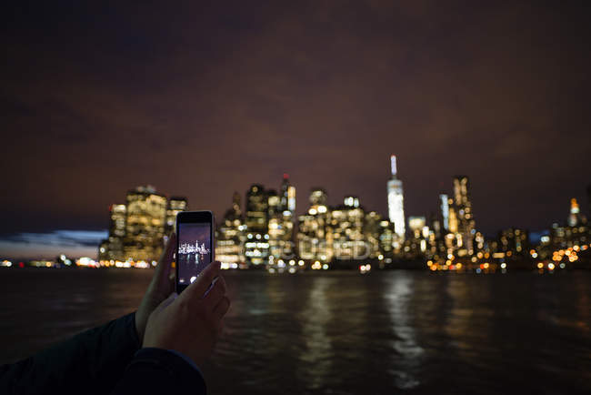 Female hands photographing skyline with smart phone — Stock Photo