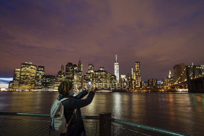 Mujer fotografiando skyline de la ciudad de Nueva York con smartphone - foto de stock