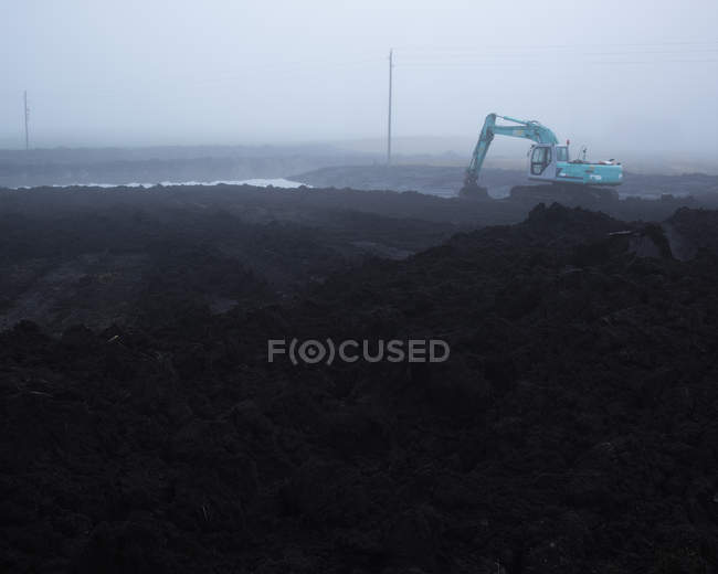 Earth mover digging on foggy day — Stock Photo