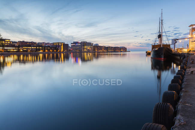 Barco amarrado y paisaje urbano al atardecer, norte de Europa - foto de stock